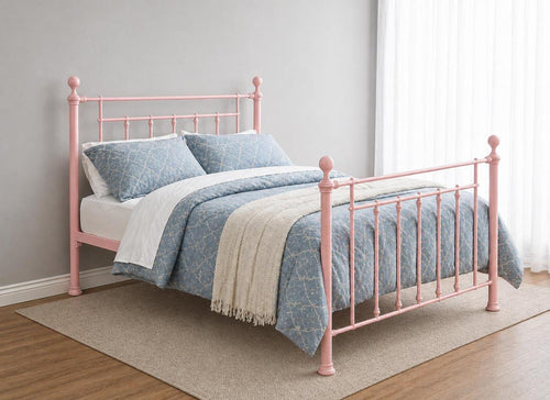 Light pink double metal bed frame with decorative finials and blue bedding.
